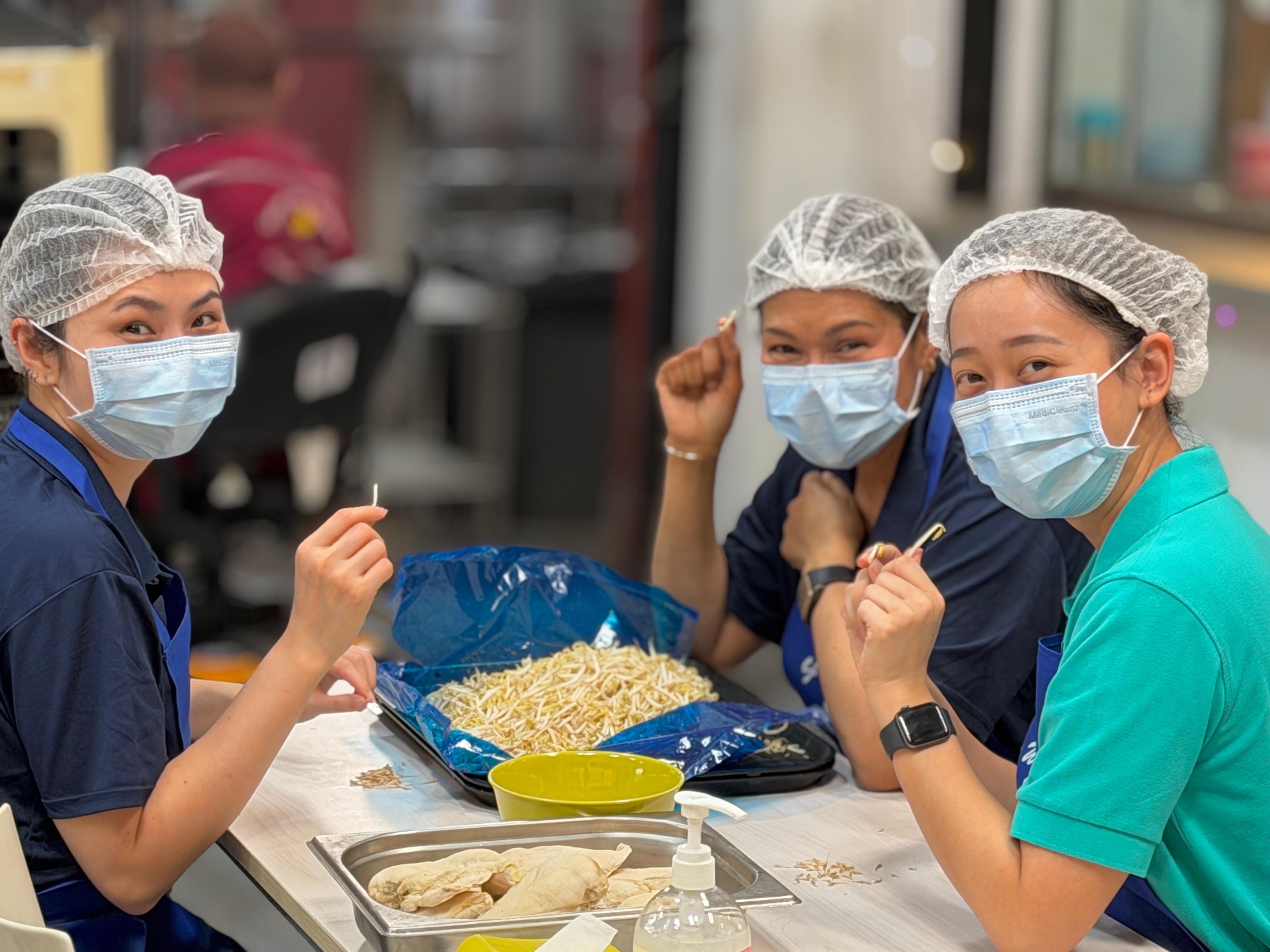 Volunteers from the TD SYNNEX Singapore DEI committee working together around a table at Dignity Kitchen during Project Dignity.