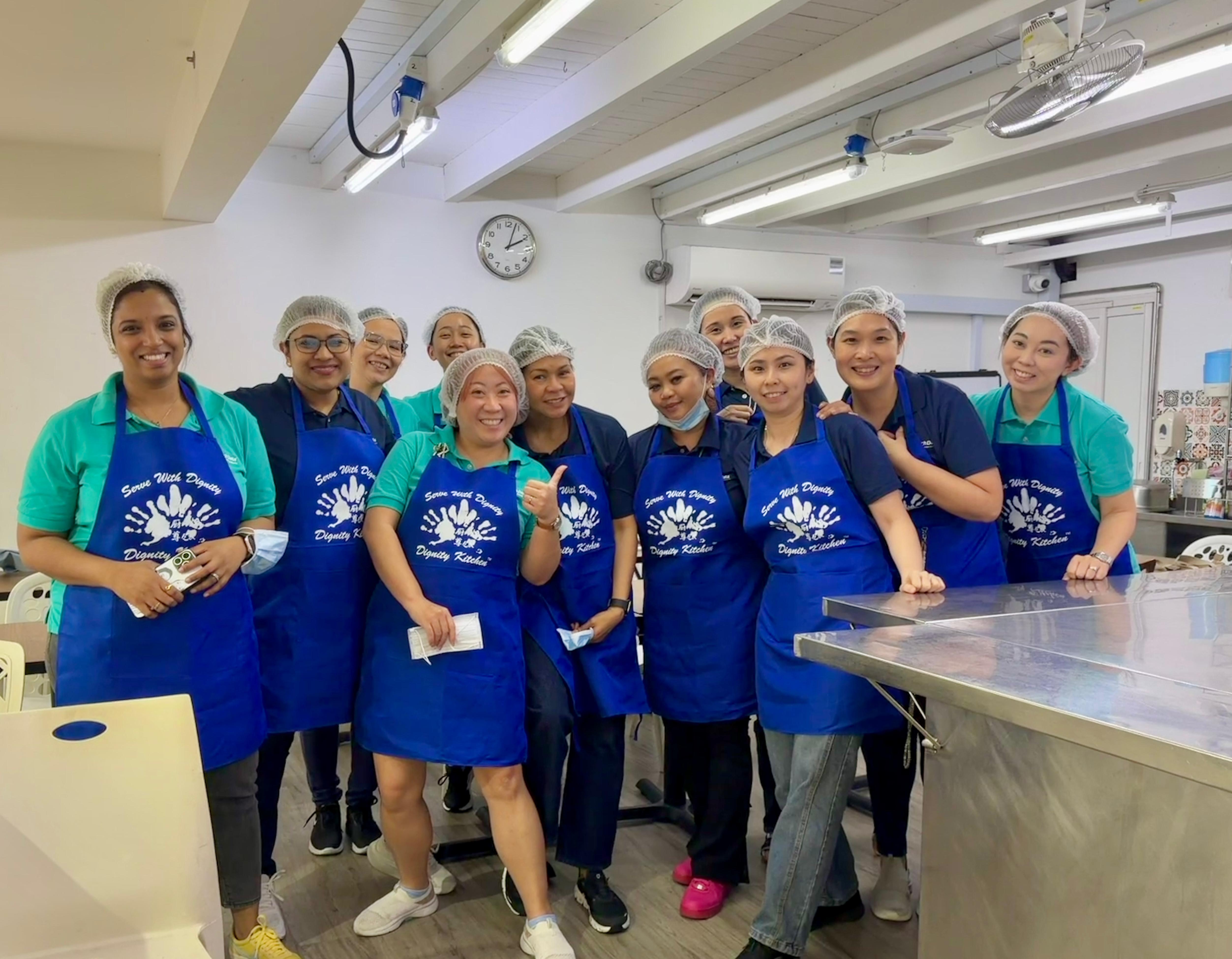 The entire TD SYNNEX Singapore DEI committee posing for a photo in Dignity Kitchen during Project Dignity volunteer time.