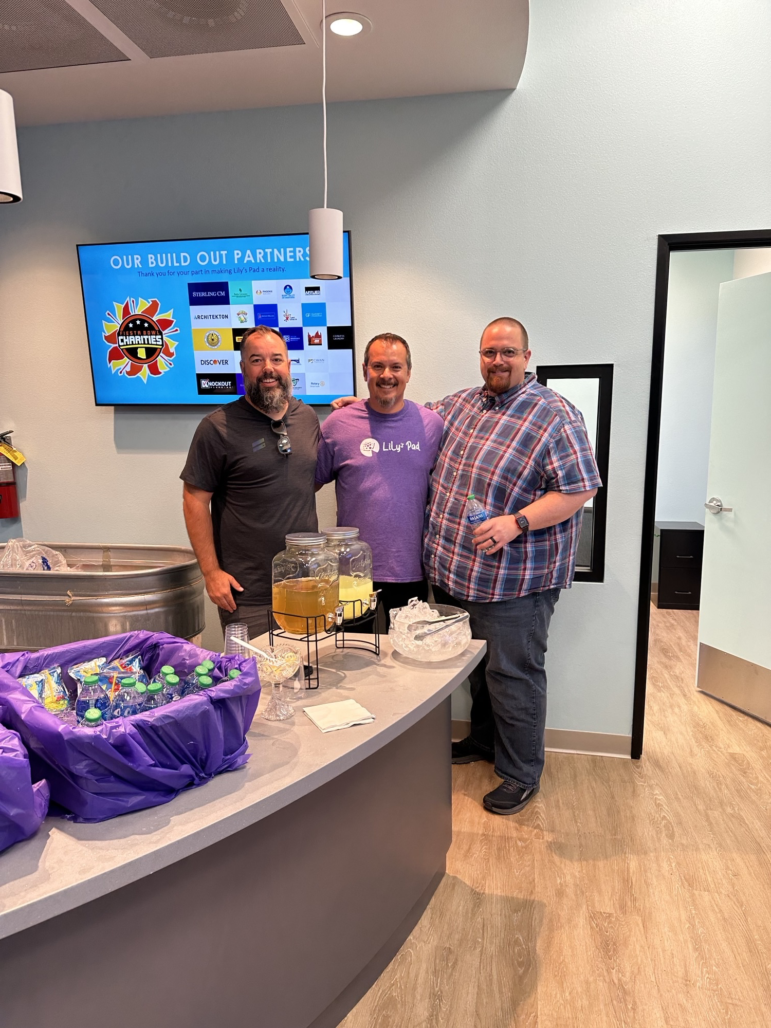 Frank Garza and his TD SYNNEX co-workers pose behind a desk filled with snacks and refreshments in the kitchen of the TD SYNNEX Gilbert, Arizona office.